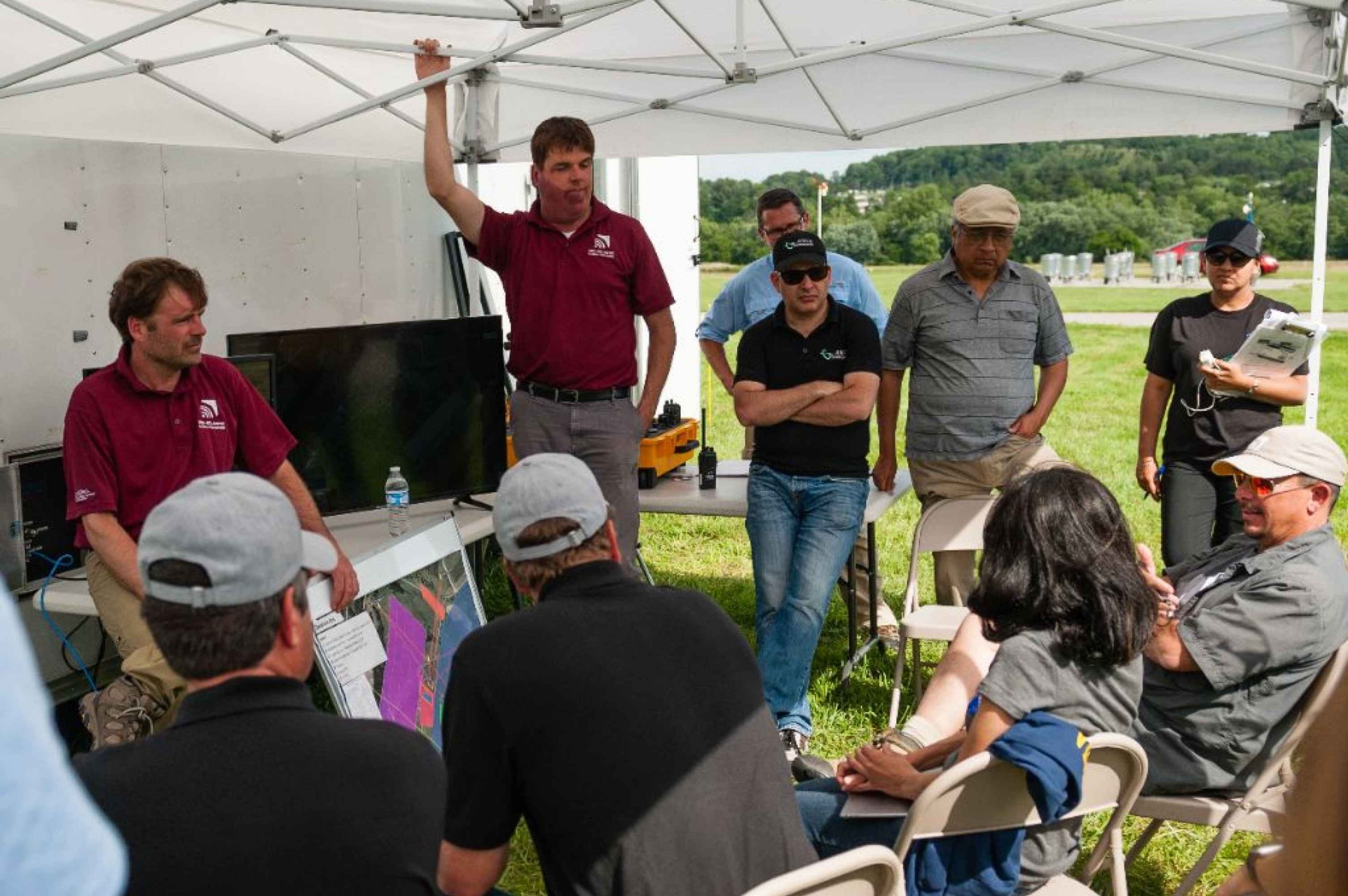 Mid-Atlantic Aviation Partnership chief engineer John Coggin, at left, leads a discussion on the unmanned traffic management research flights with personnel from NASA, Intel, Project Wing, ANRA, Fortem, and ASEC.